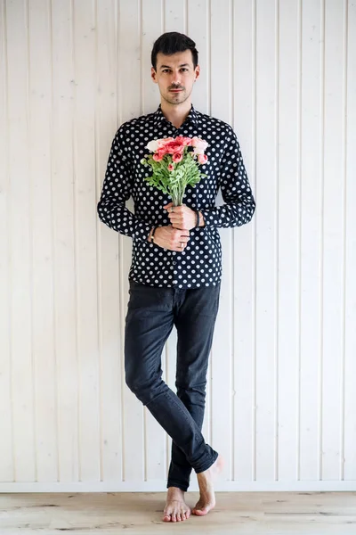 Junger Mann mit Blumen vor weißem Holzhintergrund. — Stockfoto