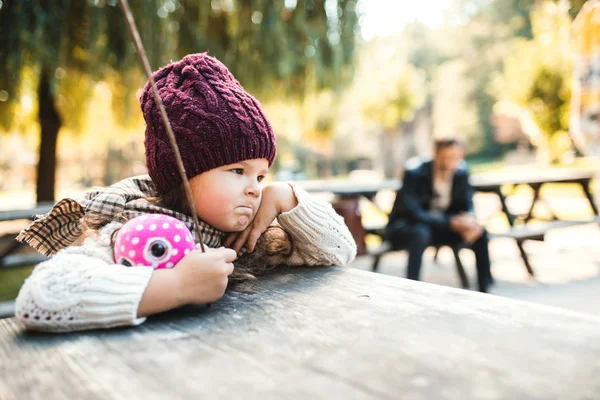 Un retrato de una niña pequeña sentada en el parque en otoño . —  Fotos de Stock