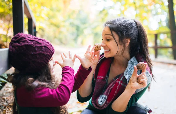 Una madre joven con una hija pequeña divirtiéndose en el bosque en otoño naturaleza . — Foto de Stock