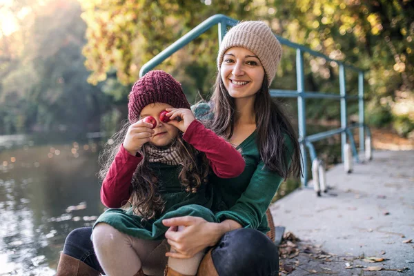 Uma jovem mãe com uma filha criança sentada na floresta no outono natureza . — Fotografia de Stock