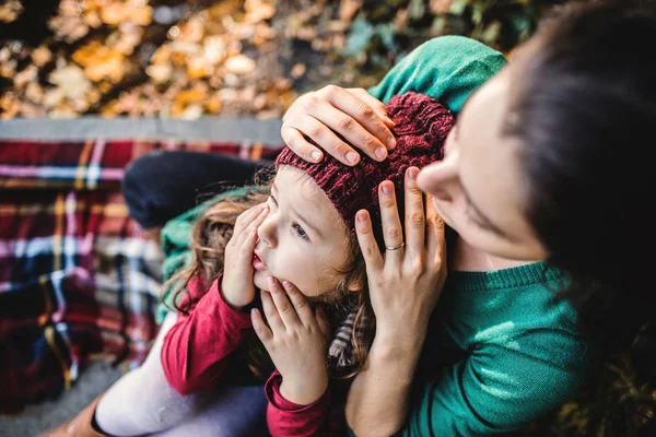 Een jonge moeder met een peuter dochter zittend in bos in de herfst natuur. — Stockfoto