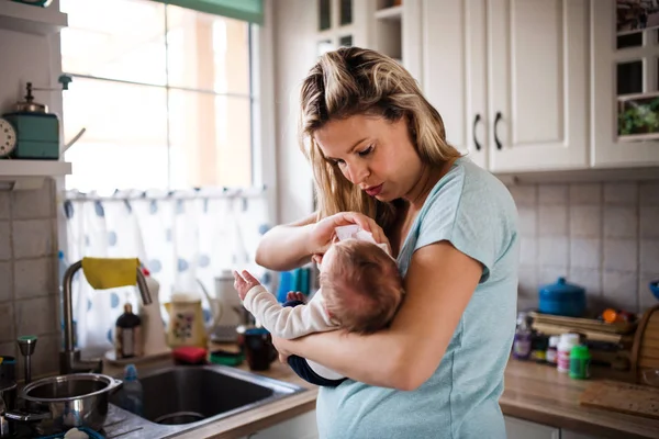 Eine schöne junge Mutter mit einem Neugeborenen zu Hause. — Stockfoto