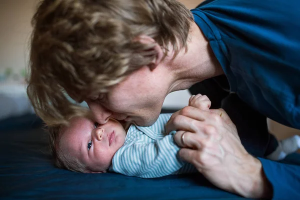 A young father kissing a newborn baby at home. — Stock Photo, Image