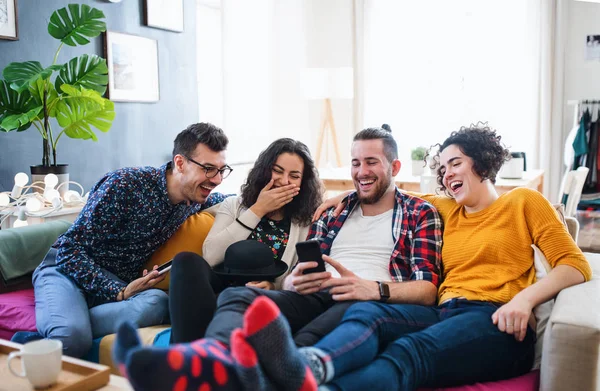 Kapalı kanepede oturan akıllı telefon ile genç arkadaş bir grup, ev paylaşım konsepti.
