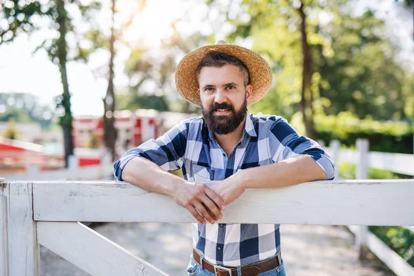 A portrait of mature man farmer standing outdoors on family farm. — Stock Photo, Image