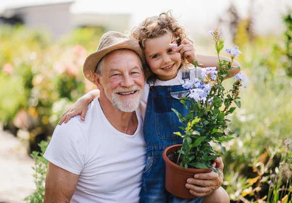 Porträt eines kleinen Mädchens mit dem Großvater im Garten des Hinterhofs, stehend. — Stockfoto