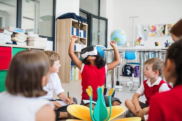 Група маленьких школярів з VR окулярами, що сидять на підлозі в класі . — стокове фото