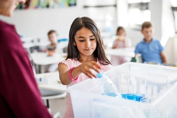 Un maestro con niños pequeños en el aula aprendiendo sobre la separación de residuos . — Foto de Stock