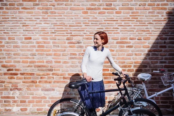 Une jeune femme d'affaires avec un vélo debout à l'extérieur. Espace de copie . — Photo