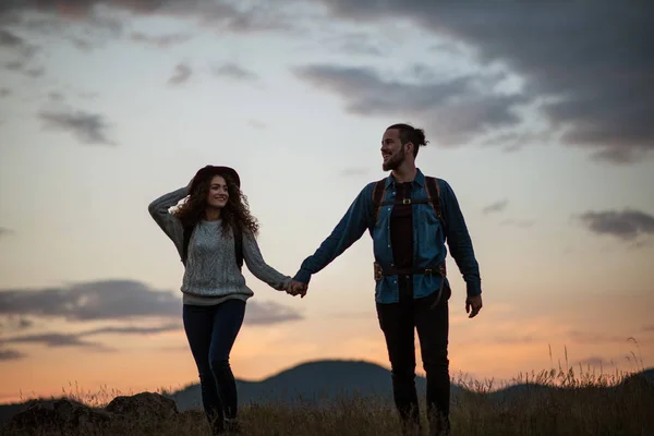 Giovani turisti coppia viaggiatori con zaini escursioni nella natura al crepuscolo . — Foto Stock