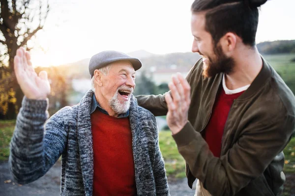 Gülen kıdemli baba ve oğlu doğada yürüyüş, yüksek beş veren.