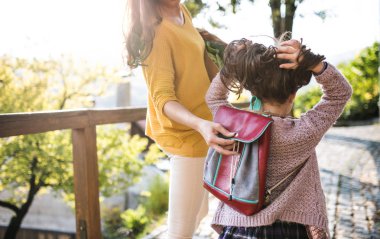 Sonbaharda şehirde küçük bir kızı ile yürüyen anne bir arka görünümü.