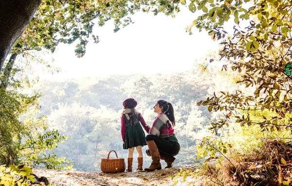 Uma visão traseira da mãe com uma filha criança em pé na floresta no outono natureza . — Fotografia de Stock