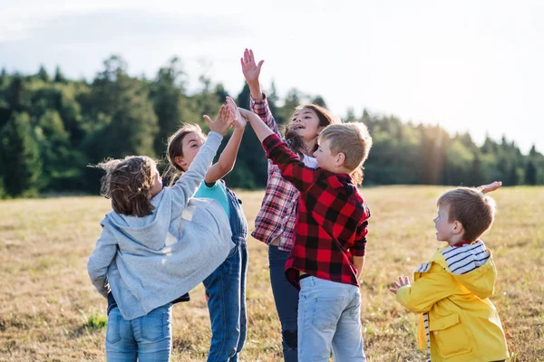 Grupp av skolbarn som står på utflykt i naturen, vilket ger höga fem. — Stockfoto