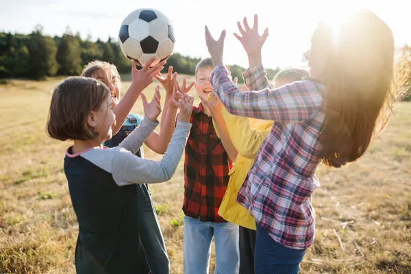 Gruppe von Schulkindern steht auf Exkursion in der Natur und spielt mit einem Ball. — Stockfoto