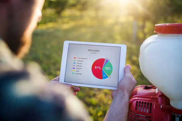 Una sección media del agricultor con la tableta de pie al aire libre en el huerto . — Foto de Stock