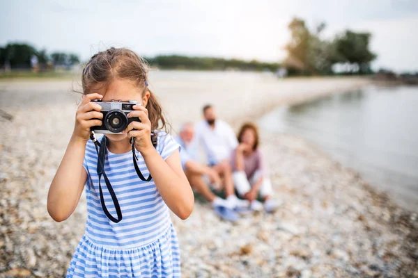 Front bild av liten flicka med kamera på en semester vid sjön, ta bilder. — Stockfoto