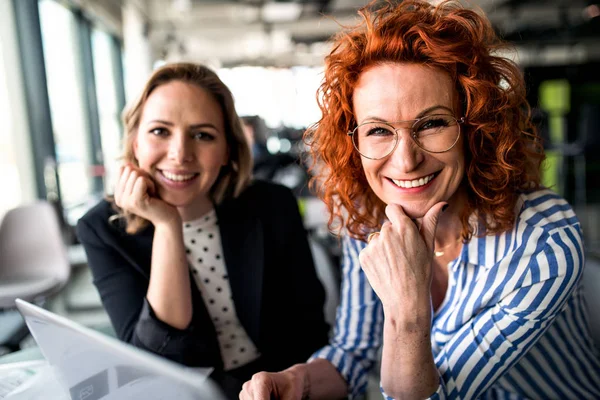 Zwei Geschäftsfrauen sitzen in einem Büro und unterhalten sich. — Stockfoto