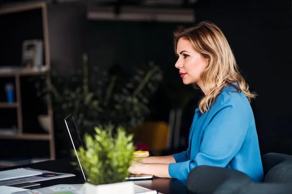 Junge Geschäftsfrau mit Laptop sitzt in einem Büro und arbeitet. — Stockfoto