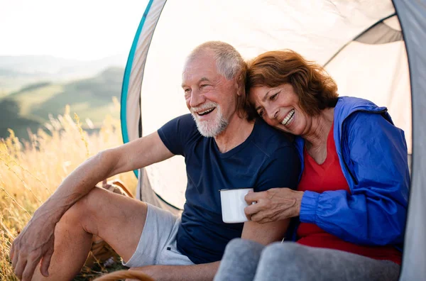 Senior pareja de turistas enamorados sentados en la naturaleza al atardecer, descansando . — Foto de Stock