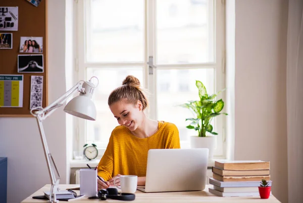 Uma jovem estudante sentada à mesa, estudando . — Fotografia de Stock