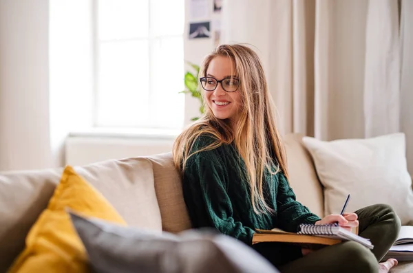 Una joven estudiante feliz sentada en el sofá, estudiando . — Foto de Stock