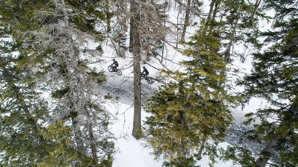 Vue aérienne de deux vététistes circulant sur la route en forêt à l'extérieur en hiver . — Photo