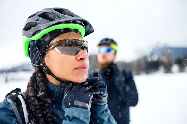 Mountain bikers standing outdoors in winter, putting on helmet. — Stock Photo, Image