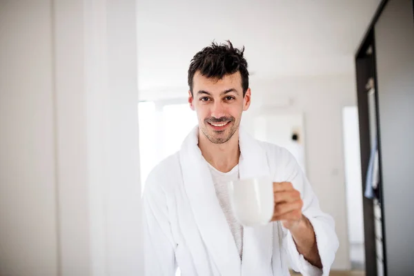 Mladý muž s kávou v ložnici ráno. — Stock fotografie