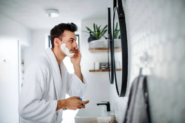 Junger Mann rasiert sich morgens im Badezimmer, Tagesablauf. — Stockfoto