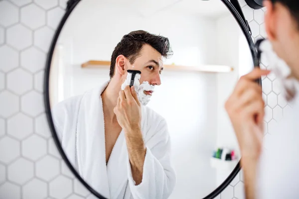 Junger Mann rasiert sich morgens im Badezimmer, Tagesablauf. — Stockfoto