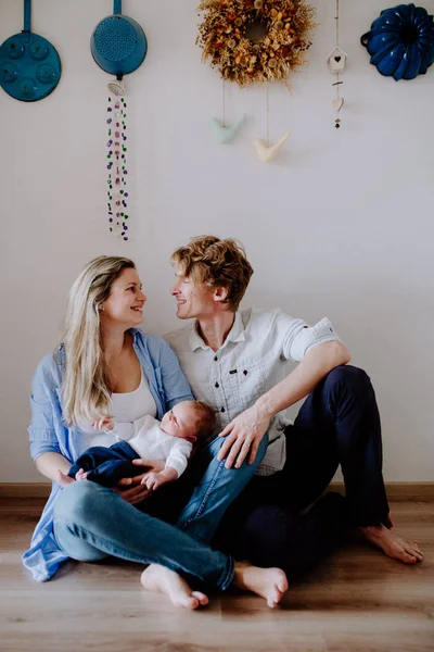 A portrait of beautiful young parents with a newborn baby at home. — Stock Photo, Image
