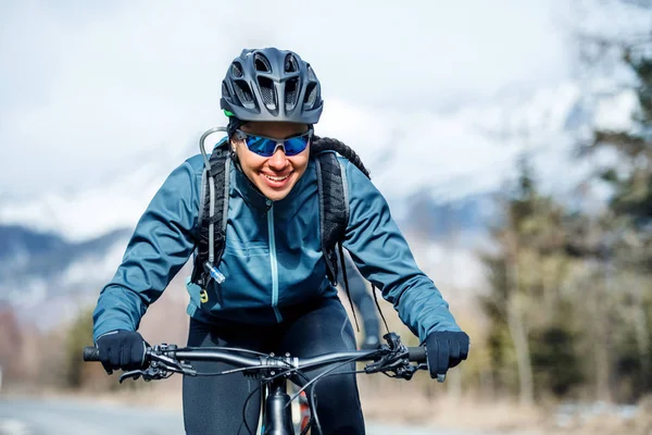 Vooraanzicht van vrouwelijke mountainbiker rijden in sneeuw buitenshuis in winter natuur. — Stockfoto