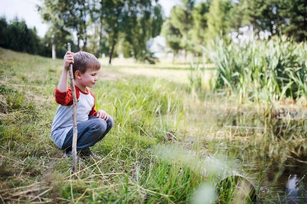 Portret van school kind op veld reis in de natuur, kijkend naar vijver. — Stockfoto