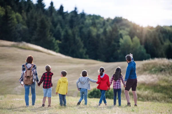 Achteraanzicht van de groep van schoolkinderen met leraar op veld reis in de natuur. — Stockfoto