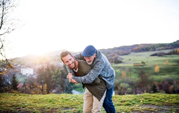 Senior vader en zijn zoon wandelen in de natuur, plezier hebben. — Stockfoto