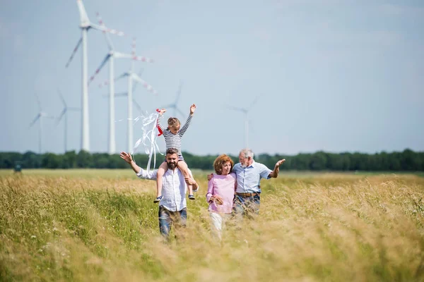 多代家庭在风电场的田地里散步. — 图库照片