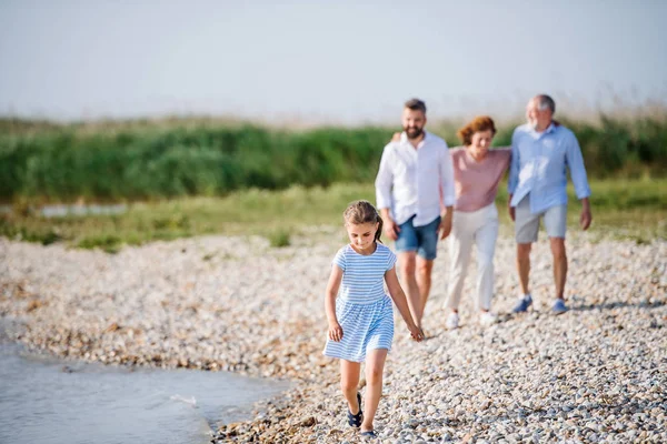 Famiglia multigenerazionale in vacanza passeggiando lungo il lago, tenendosi per mano . — Foto Stock