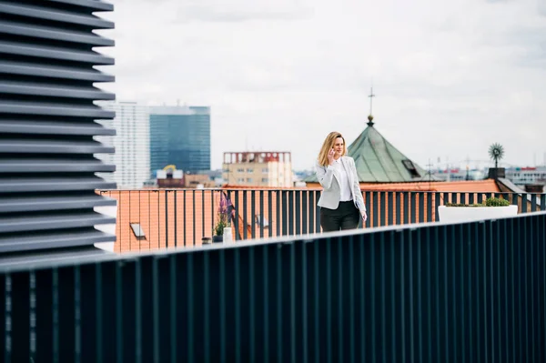 Eine junge Geschäftsfrau mit Smartphone steht auf einer Terrasse und arbeitet. — Stockfoto