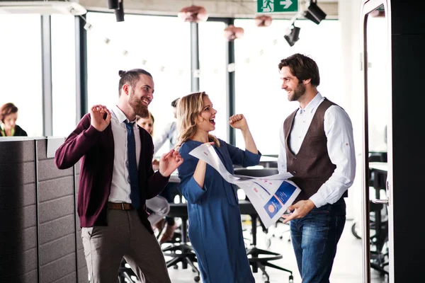 Eine Gruppe von Geschäftsleuten steht in einem Büro und drückt ihre Begeisterung aus. — Stockfoto