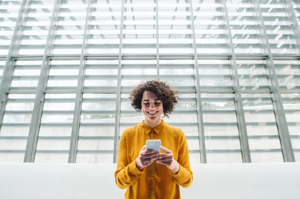 Giovane studentessa o donna d'affari con smartphone in biblioteca o in ufficio . — Foto Stock