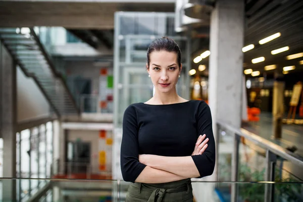 Un retrato de una joven empresaria parada en el pasillo fuera de la oficina, con los brazos cruzados . —  Fotos de Stock