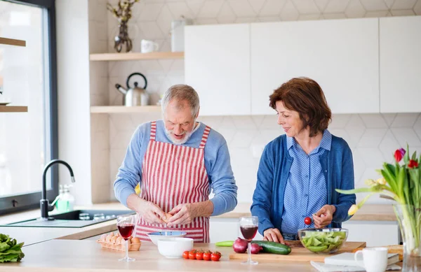 Um retrato de casal sênior dentro de casa, cozinhar . — Fotografia de Stock