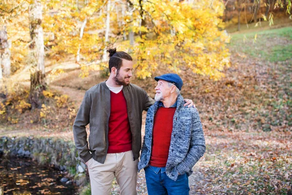 Senior vader en zijn zoon wandelen in de natuur, praten. — Stockfoto