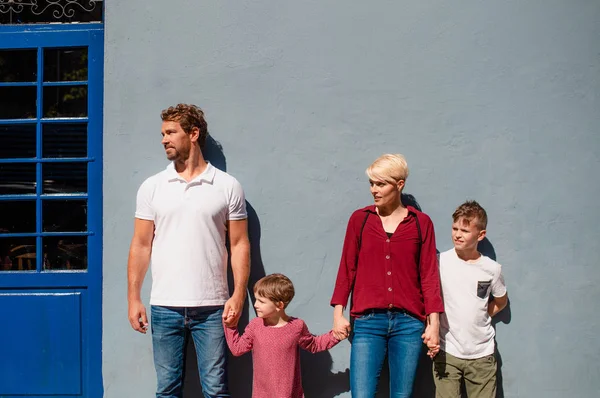Etunäkymä nuorelle perheelle, jossa kaksi pientä lasta seisoo ulkona kaupungissa . — kuvapankkivalokuva