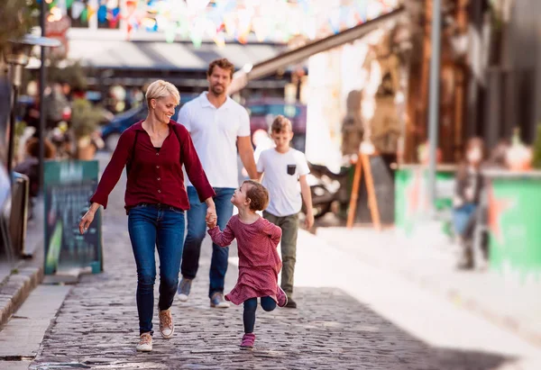 Jeune famille avec deux jeunes enfants marchant à l'extérieur en ville en vacances . — Photo