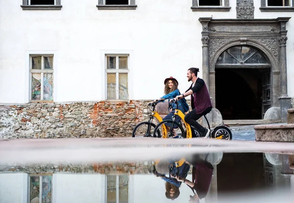 Jeunes touristes couple voyageurs avec scooters électriques dans une petite ville . — Photo