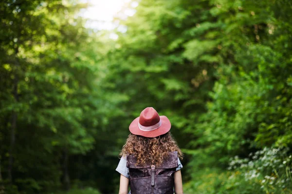 Vista posteriore di giovane turista viaggiatore donna con zaino a piedi nella natura . — Foto Stock