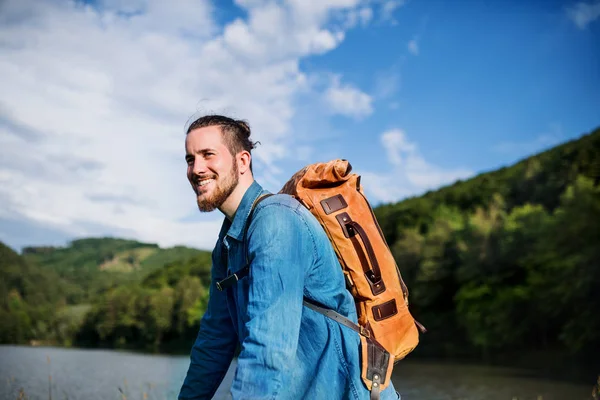 Junger Tourist mit Rucksack steht in der Natur und ruht sich aus. — Stockfoto