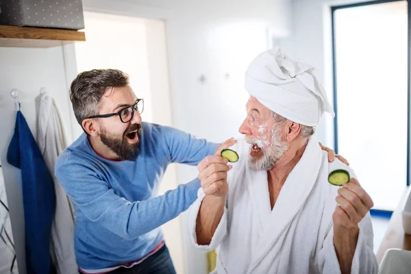 Un figlio hipster adulto e padre anziano in bagno in casa, divertendosi . — Foto Stock
